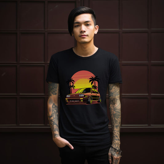 Person wearing a black t-shirt with a graphic design of a sunset and car on a dark background