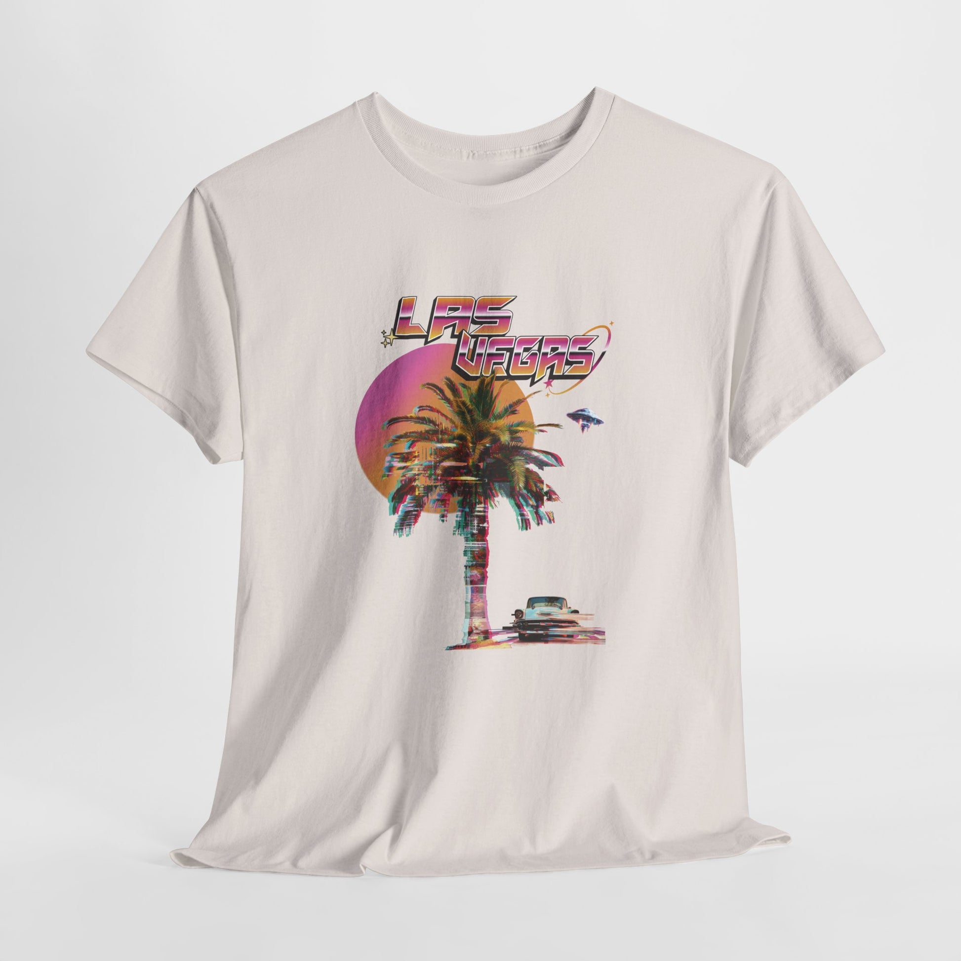 An off white t-shirt with a retro glitch Las Vegas graphic featuring a palm tree, a sunset, and UFOs over a desert landscape.