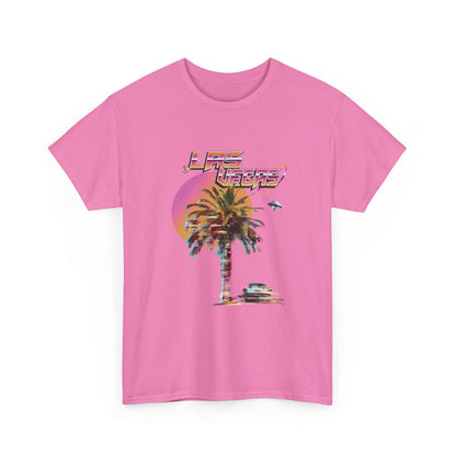 A flamingo pink t-shirt with a retro Las Vegas glitch graphic featuring a palm tree, a sunset, and UFOs over a desert landscape.