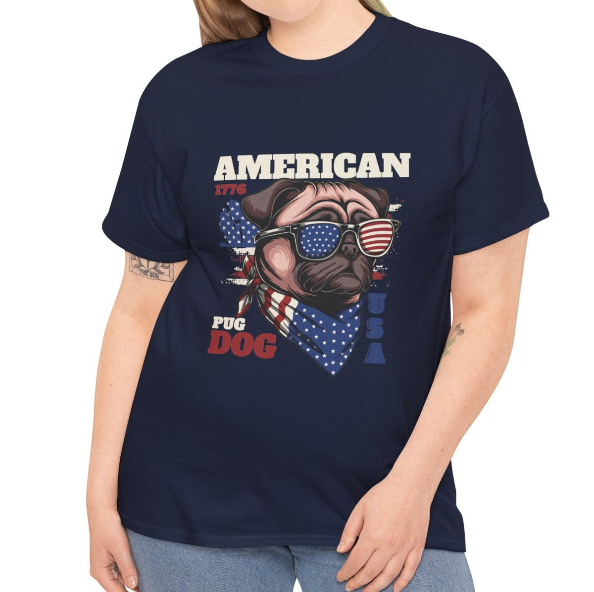 A woman wearing a navy blue graphic t-shirt with a patriotic 'American Pug Dog USA' design featuring a pug wearing sunglasses and a bandana. The model is cropped from the neck down, wearing light blue jeans against a plain white background.