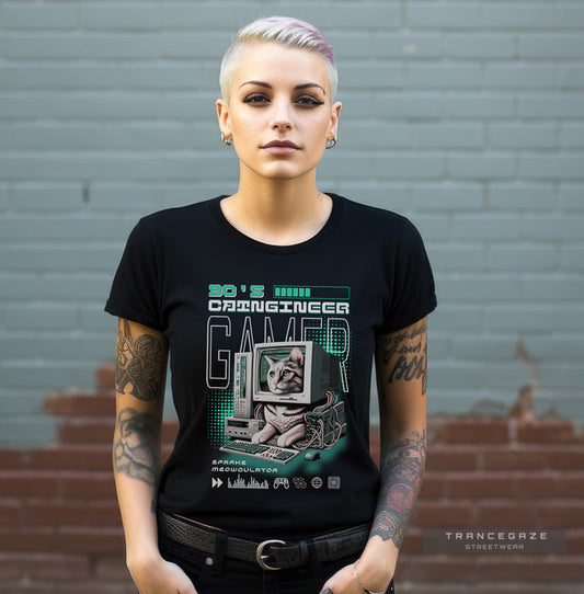 Person wearing a black t-shirt with a graphic design of a cat on a computer, standing against a gray brick wall.