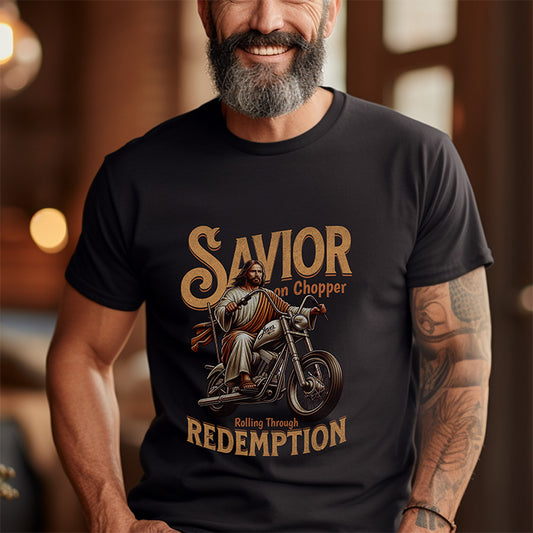 Man wearing a black t-shirt with a graphic design of a man on a motorcycle and text 'Savior on Chopper Rolling Through Redemption'.